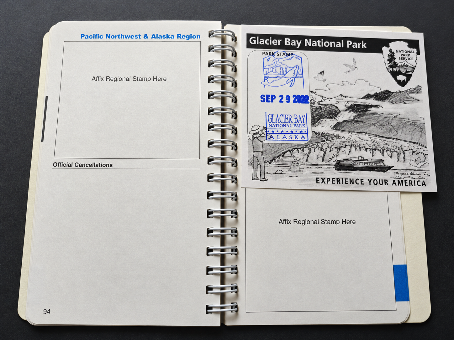 Open National Parks Passport book with a Glacier Bay National Park card bearing a blue cancellation stamp.